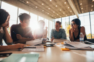 Group of young people sitting at table reading books