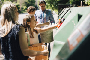 Family and children throwing garbage in bin at roadside