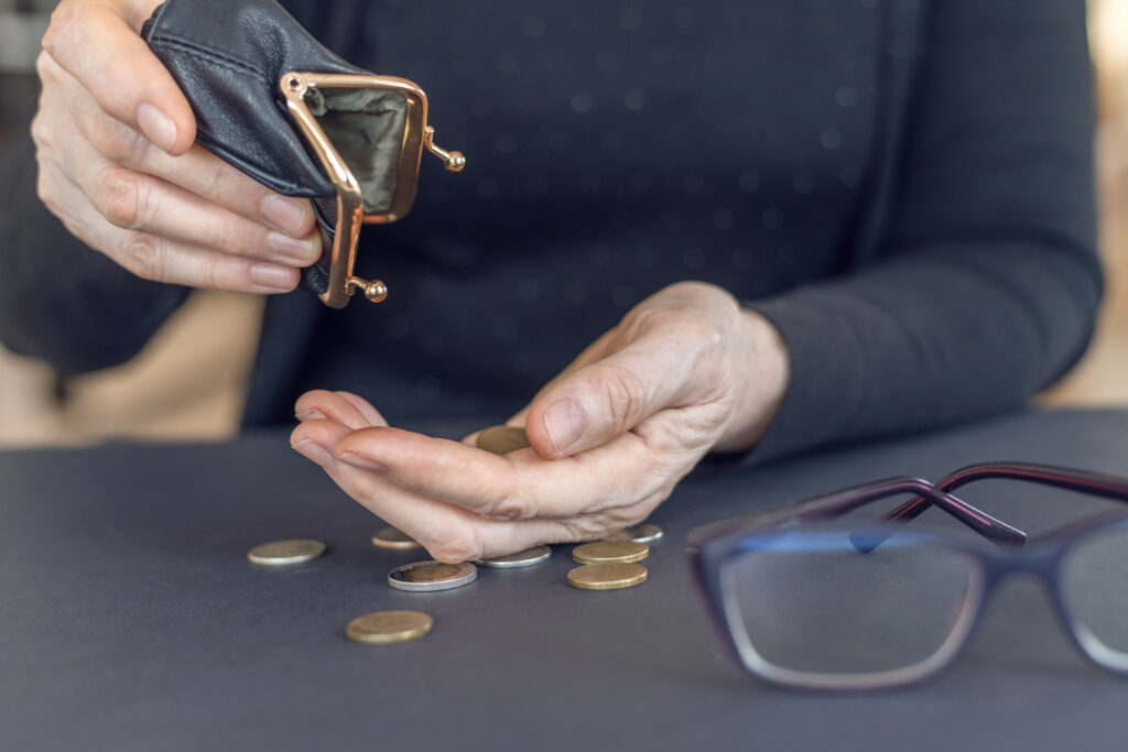 An elderly woman holds an open empty wallet in her hands, the concept of poverty, pension