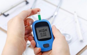 mano-que-sostiene-un-medidor-de-glucosa-de-sangre-que-mide-el-azucar-de-sangre-el-fondo-es-un-estetoscopio-y-un-archivo-de-carta